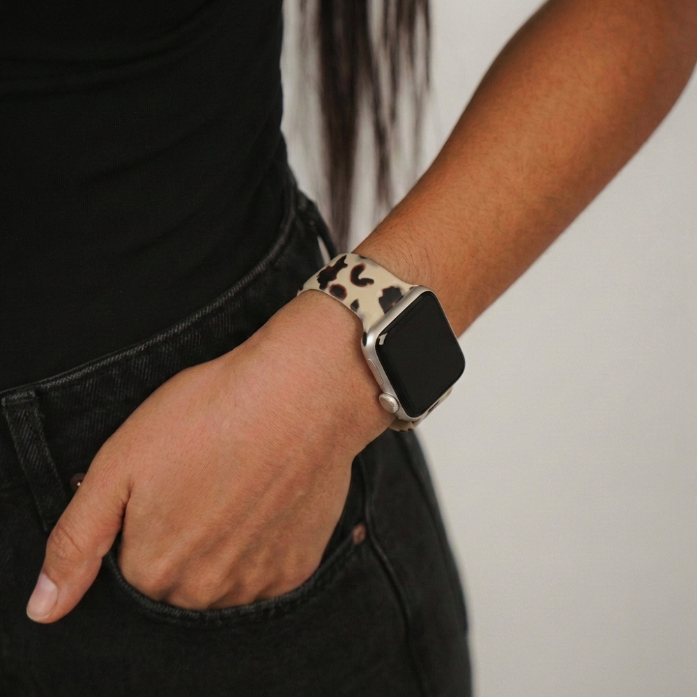 Milky ivory tortoise Apple Watch strap on wrist, paired with black shirt and pants, hand casually in pocket.