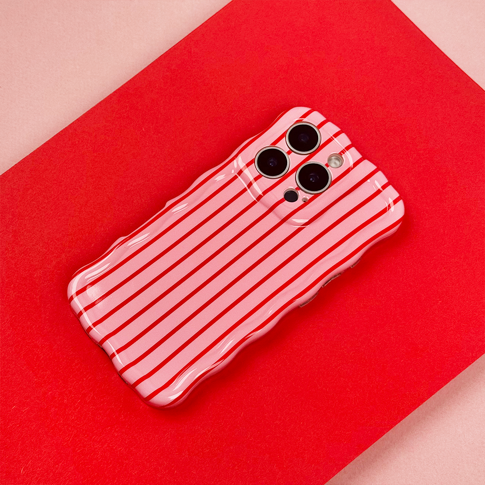 A smartphone with a wavy-edged case featuring red and white vertical stripes lies on a red and pink background.
