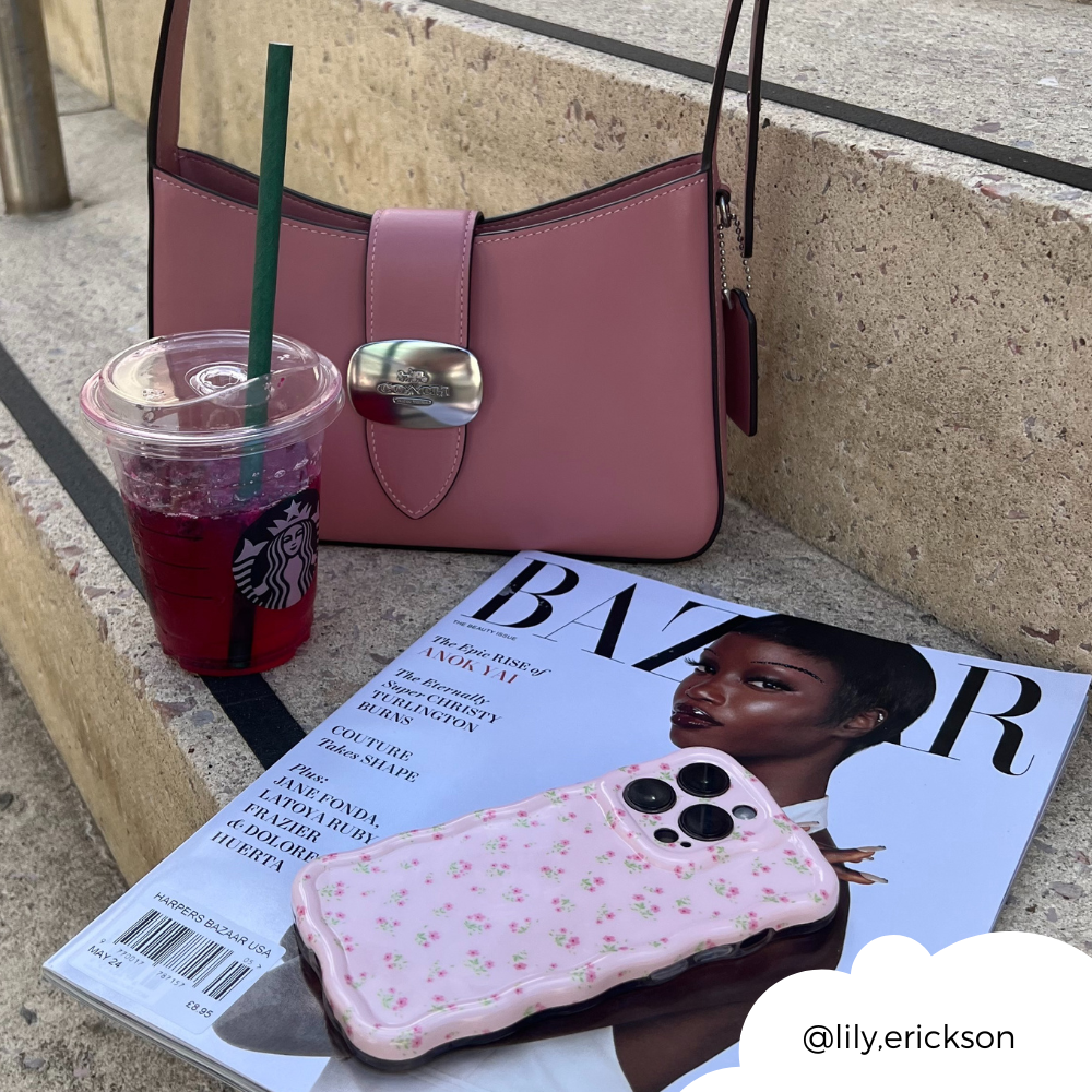 A pink handbag, a Starbucks drink with a green straw, a Harper's Bazaar magazine featuring a woman on the cover, and Coconut Lane's Wavy Phone Case in Ditsy Floral Pink are placed on concrete steps. The Instagram handle @lily.erickson is positioned in the bottom right corner within a white cloud shape.