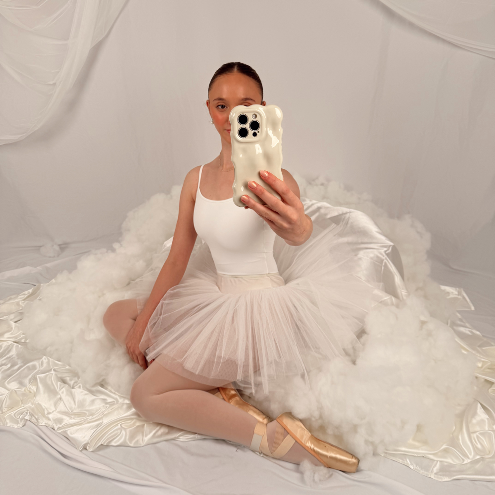 Girl in ballet outfit surrounded by clouds holding the 3D Bubble Phone Case Cloud Dancer