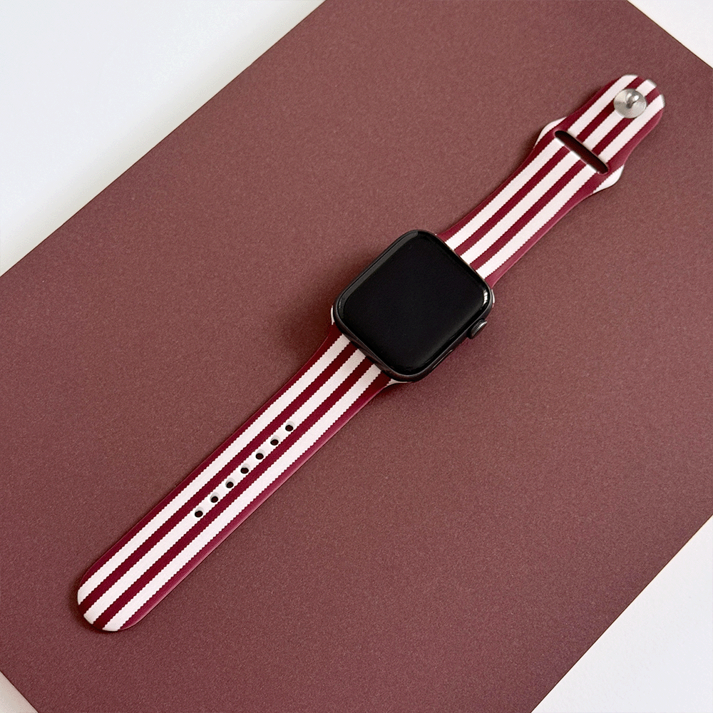 Burgundy and light pink striped Apple Watch Strap, attached to a black Apple Watch.