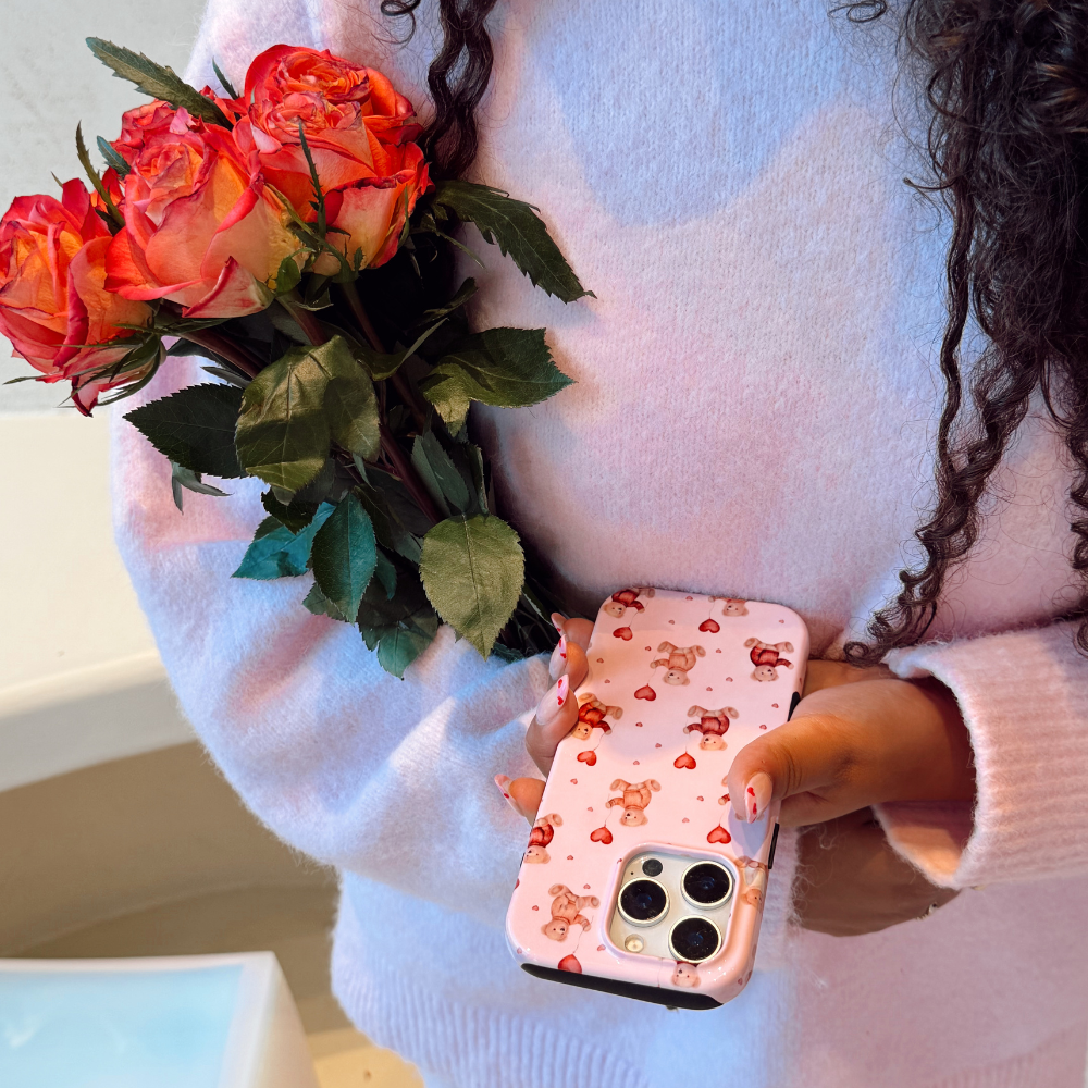 Person holding a bouquet of red roses and a phone with a floral case.