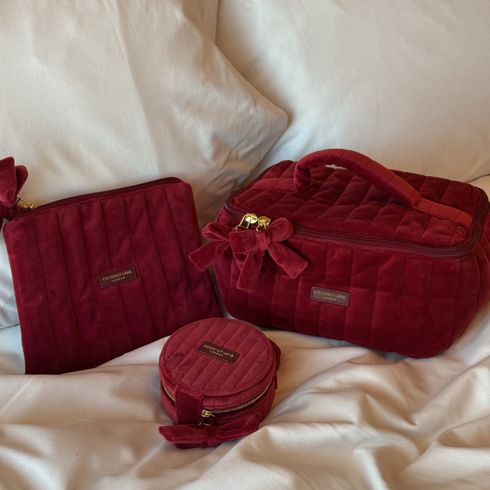 Burgundy velvet cosmetic bag, box and pouch with a quilted design, top handle, bow detail, and gold-tone hardware.