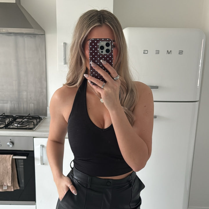 Woman taking a mirror selfie in a kitchen with brown & blue polka dot tough case