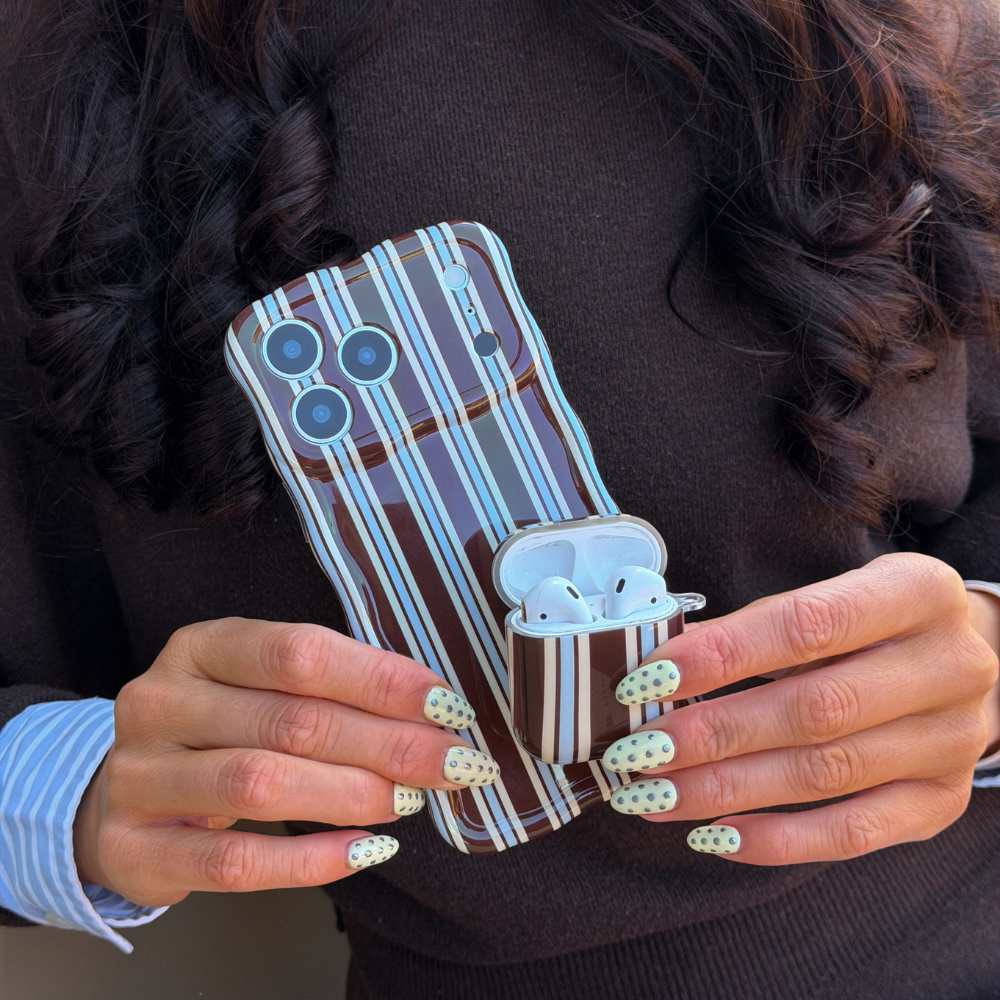 Girl holding Brown and Blue Stripe AirPods Case next to matching wavy phone case