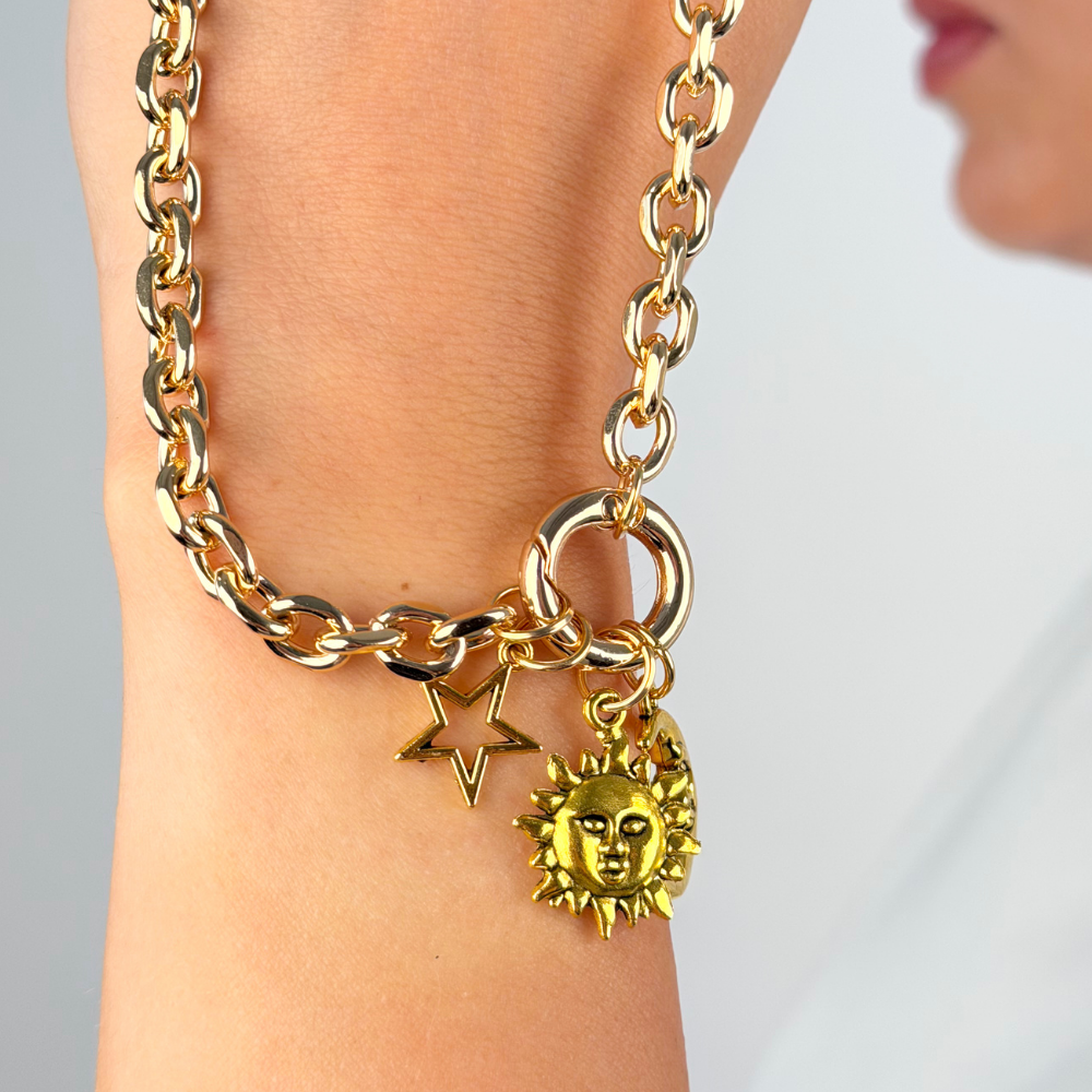 Close up studio image sun charm attached to gold strap