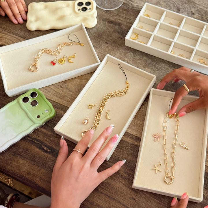 3 different phone straps from charm studio next to phones showing charms attached. 