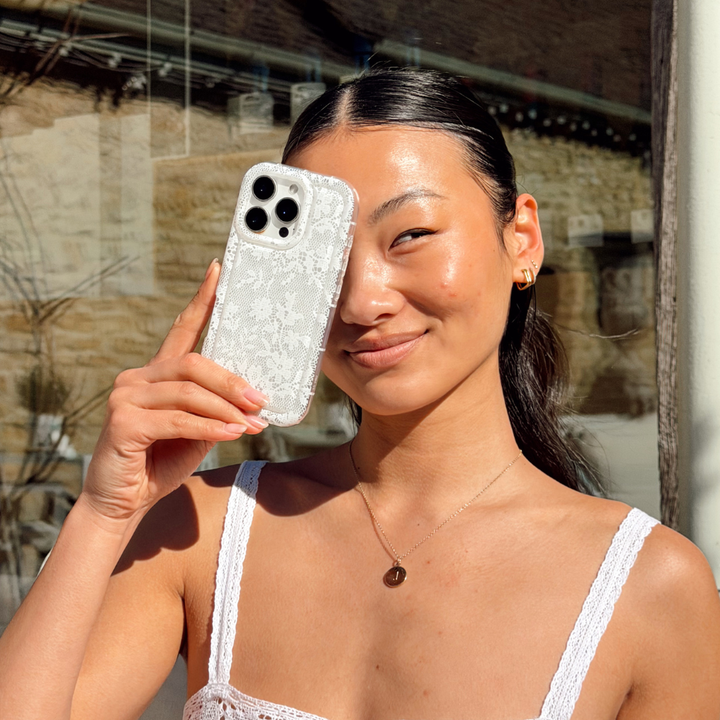 girl with the clear white lace phone case in front of her face smiling