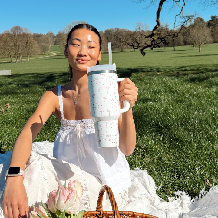 Girl holding up her Dainty Bows Tumbler at a spring picnic