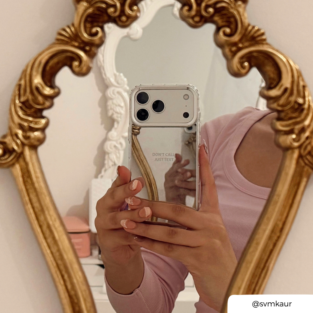 Woman taking a mirror selfie, holding an iphone in a mirrored phone case with the text "don't call just text" printed on the back. 