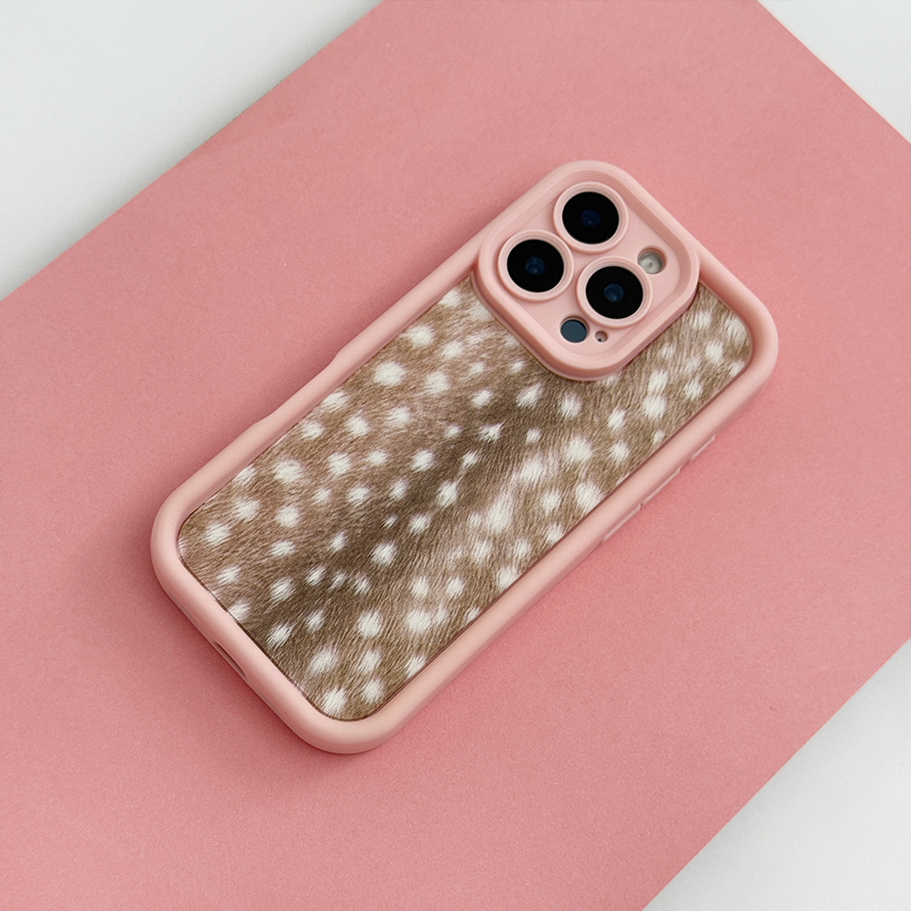 A phone case with pink edging and brown fawn-print center featuring white spots, shown on a phone against a solid pink background.