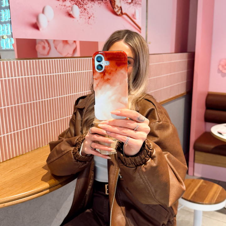 Girl taking a selfie with the Iced Latte Tough Phone Case in a cafe setting