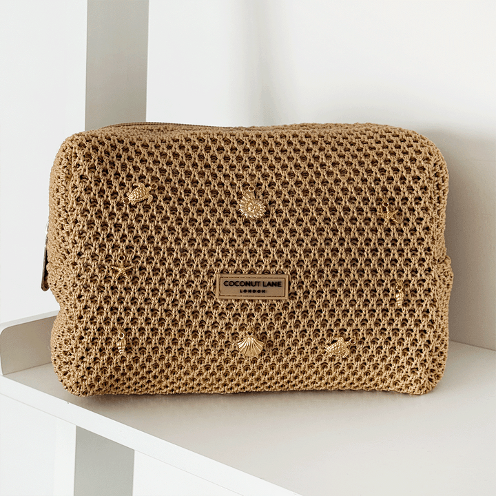 Brown woven makeup bag with gold charms attached.