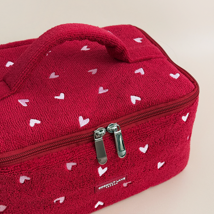 Red textured bag with white heart patterns and a visible brand logo on a beige background