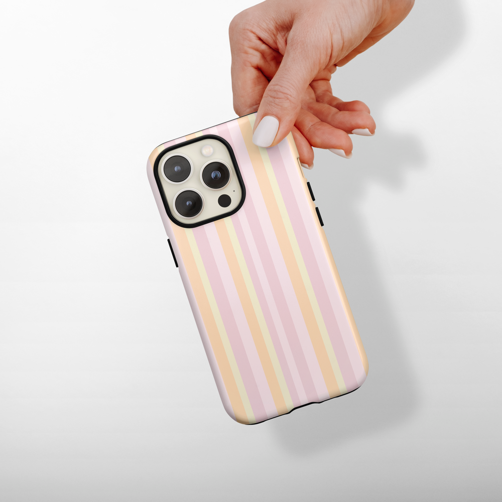 Phone case with pink and yellow stripes held by a hand on a light gray background