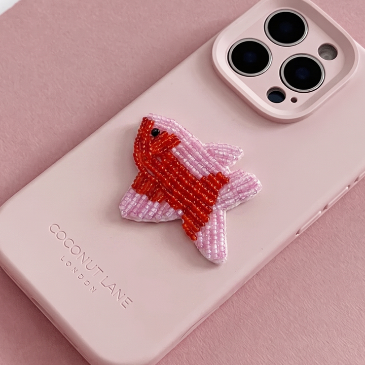 Red and pink 3D fish made from beads and sequins, on top of a pink Coconut Lane Phone Case. 