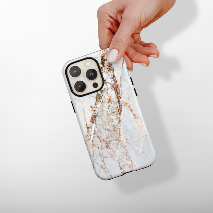 Hand holding a phone case with a marble design on a light background