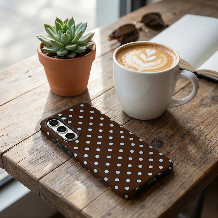 Samsung tough case with brown and blue polka dots, shown on a table beside a latte, succulent, and sunglasses.
