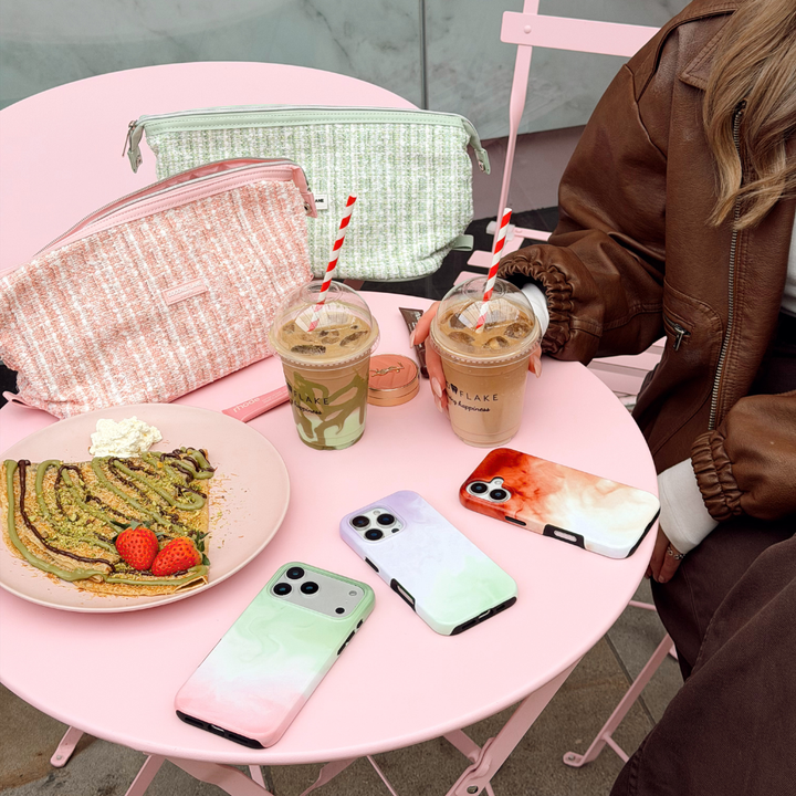 An aesthetic cafe pink table with matcha phone cases and makeup bags
