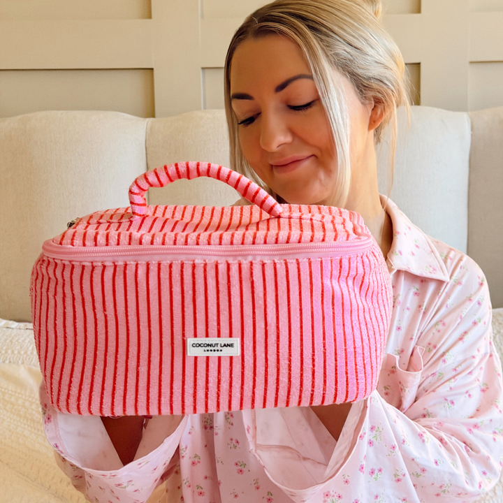 Girl holding up Cherry Stripes Vanity Case in a bedroom setting