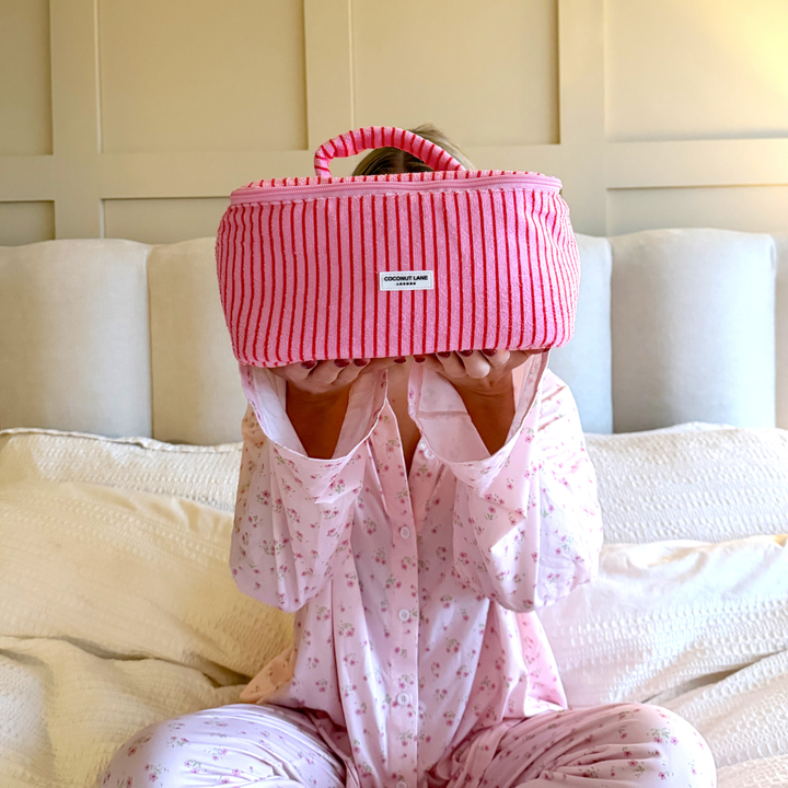 Girl in bed in pyjamas holding up the Cherry Stripes Vanity Case