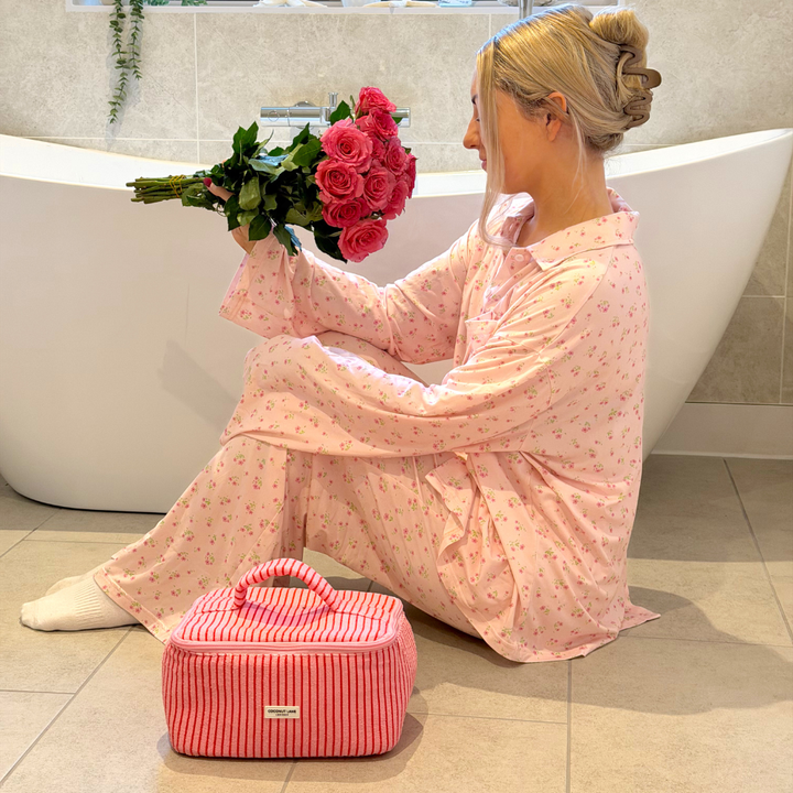 Girl sat next to bath smelling a bunch of roses next to the Cherry Stripes Vanity Case