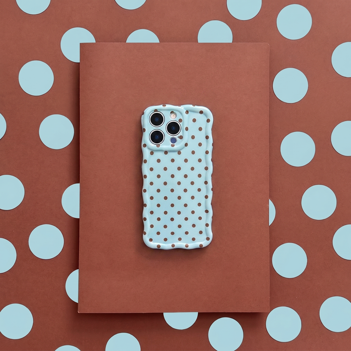Phone case with polka dot pattern on a brown surface with blue polka dots