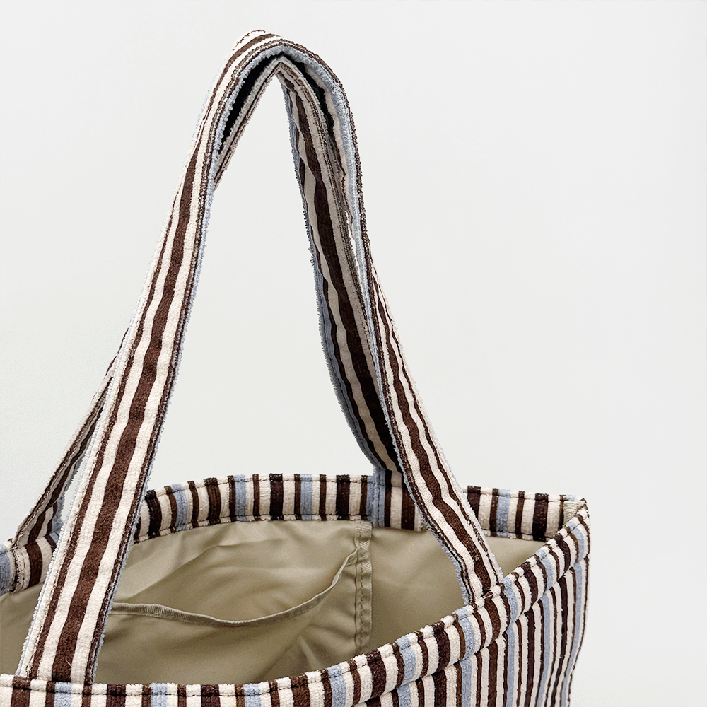Brown and blue striped tote bag with beige, towel-like interior lining.