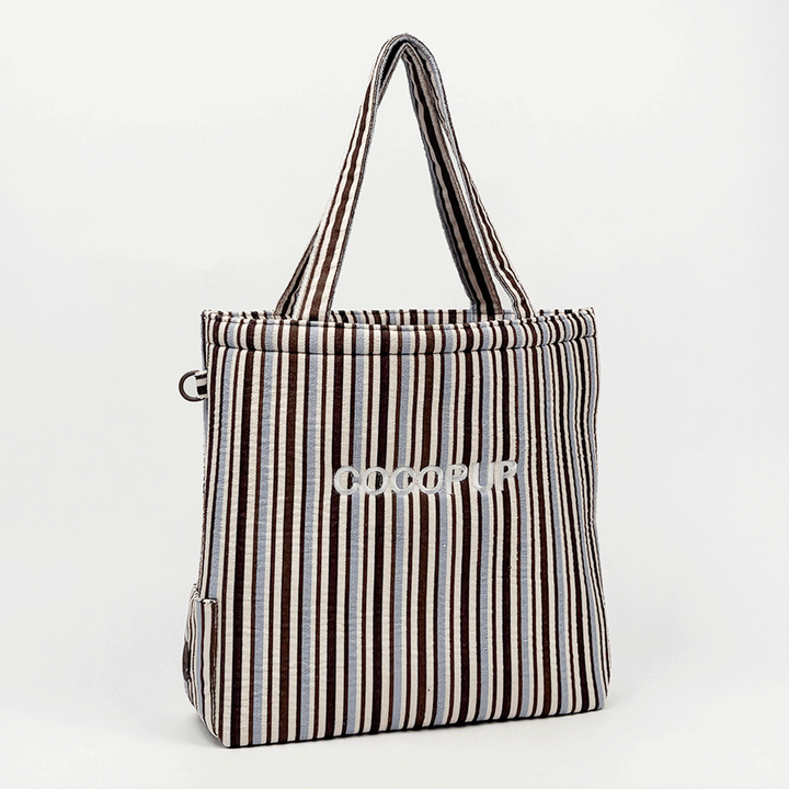 Tote bag with brown and blue stripes, towel-inspired texture, and sturdy handles.