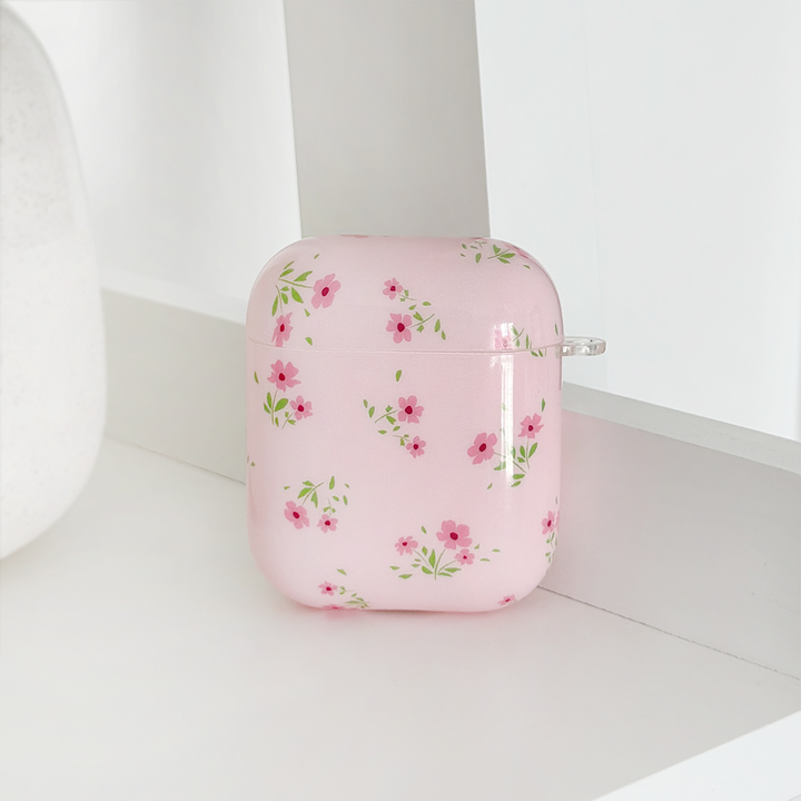 The AirPods Case - Ditsy Floral Pink by Coconut Lane features a delicate pattern of small pink flowers and green leaves displayed against a white background. This sleek, glossy case showcases the intricate design beautifully through IMD Print Technology.