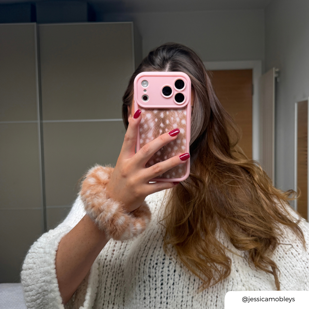 Girl in mirror with brown hair holds a pink and fawn print phone case