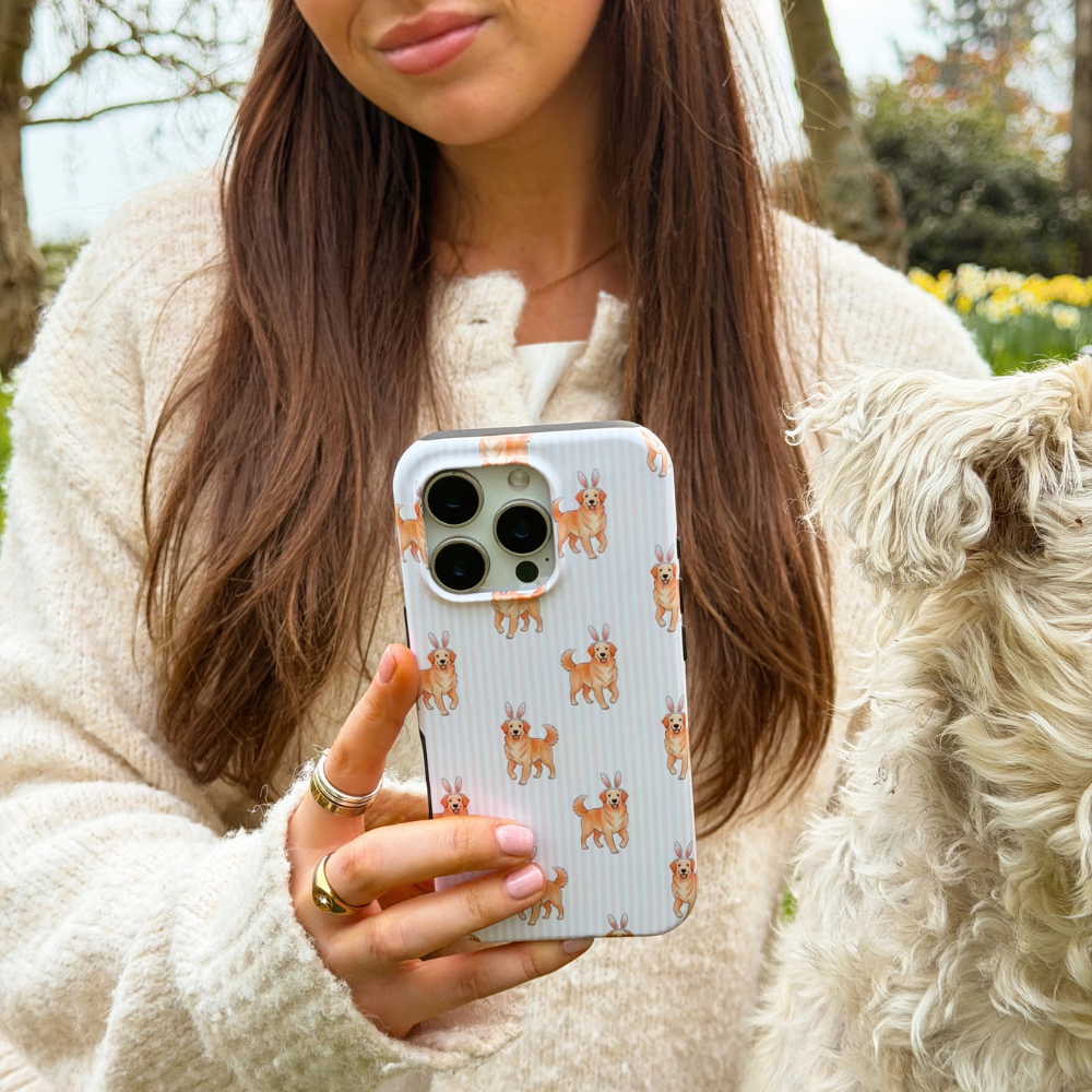 Girl sat next to white dog holding her hoppy pup tough phone case