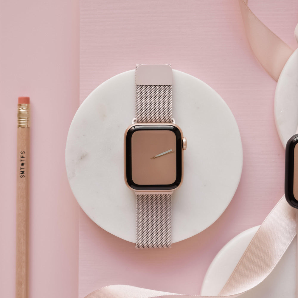 Powder pink magnetic chain Apple Watch strap by Coconut Lane on a white surface with a pencil and pink ribbon nearby.