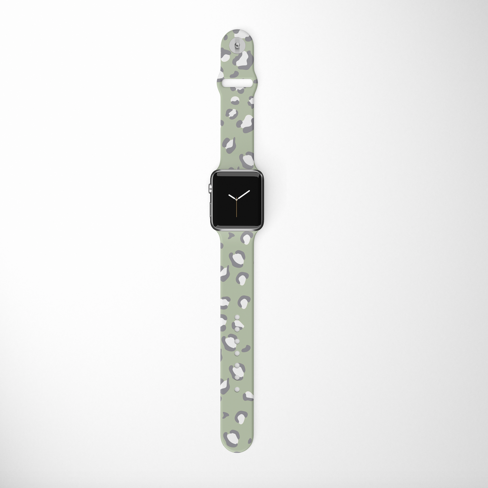 A Coconut Lane Sage Leopard Apple Watch Strap is showcased, featuring a rectangular black screen and a light green silicone band with a white and gray leopard print pattern, set against a plain, light background.